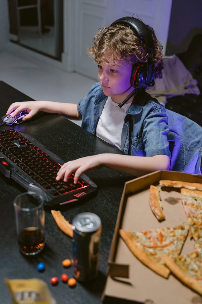 story-02 Child with curly hair focused on gaming, surrounded by pizza and gadgets. A modern day gaming scene.